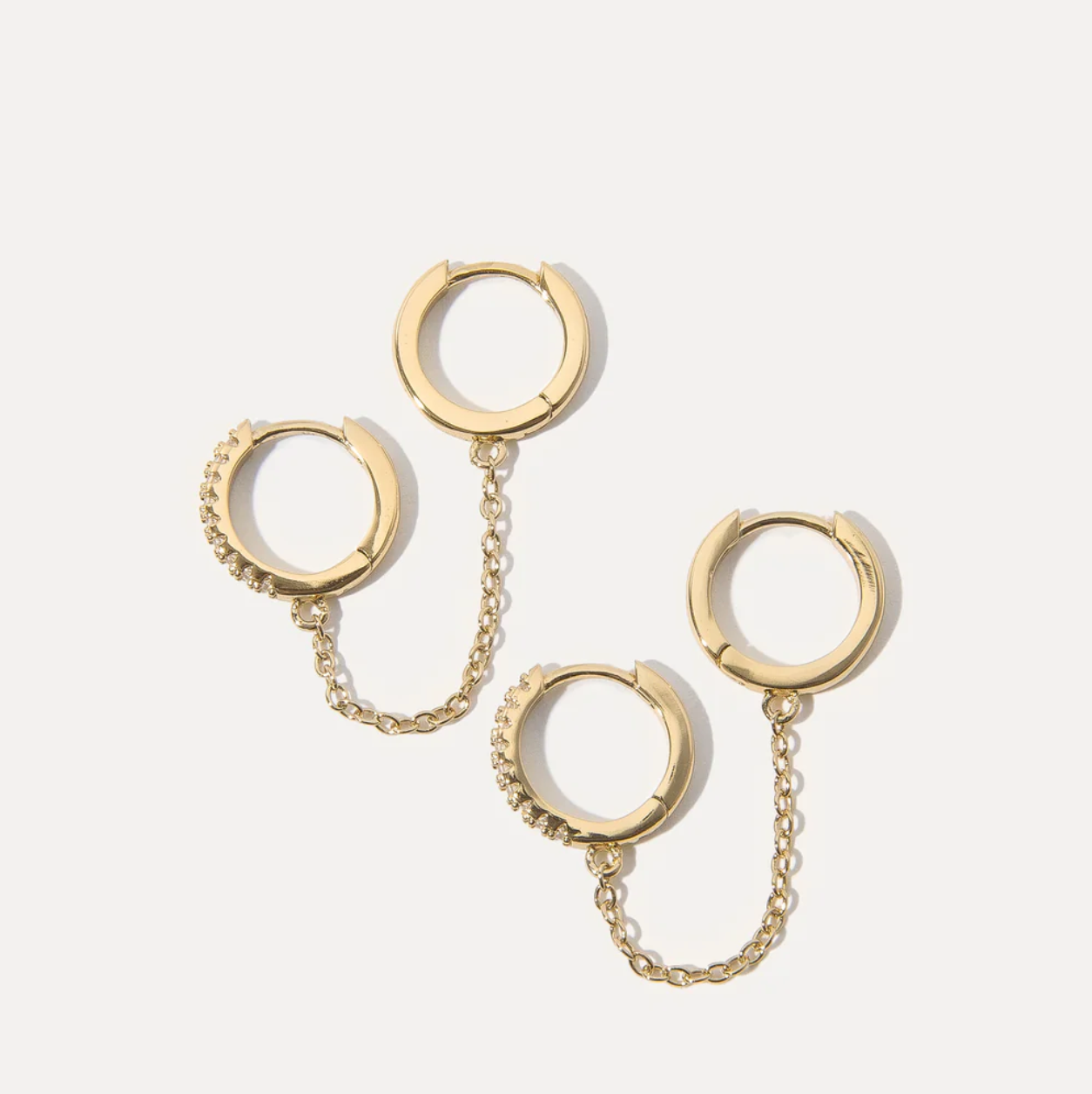 Gold hoop earrings connected with a chain on a white background