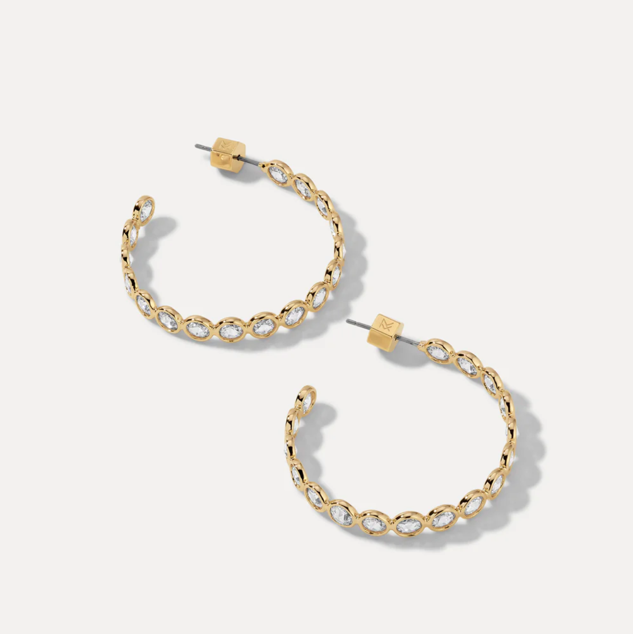 Gold hoop earrings with clear gemstones on a white background