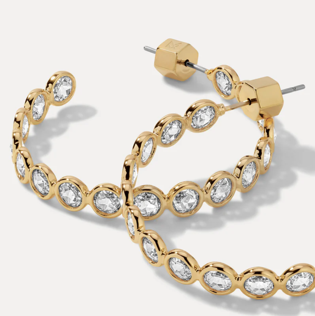 Gold hoop earrings with clear gemstones on a white background