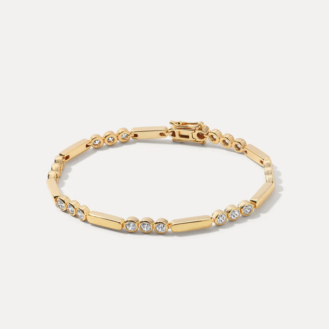 Gold bracelet with clear stones on a light gray background
