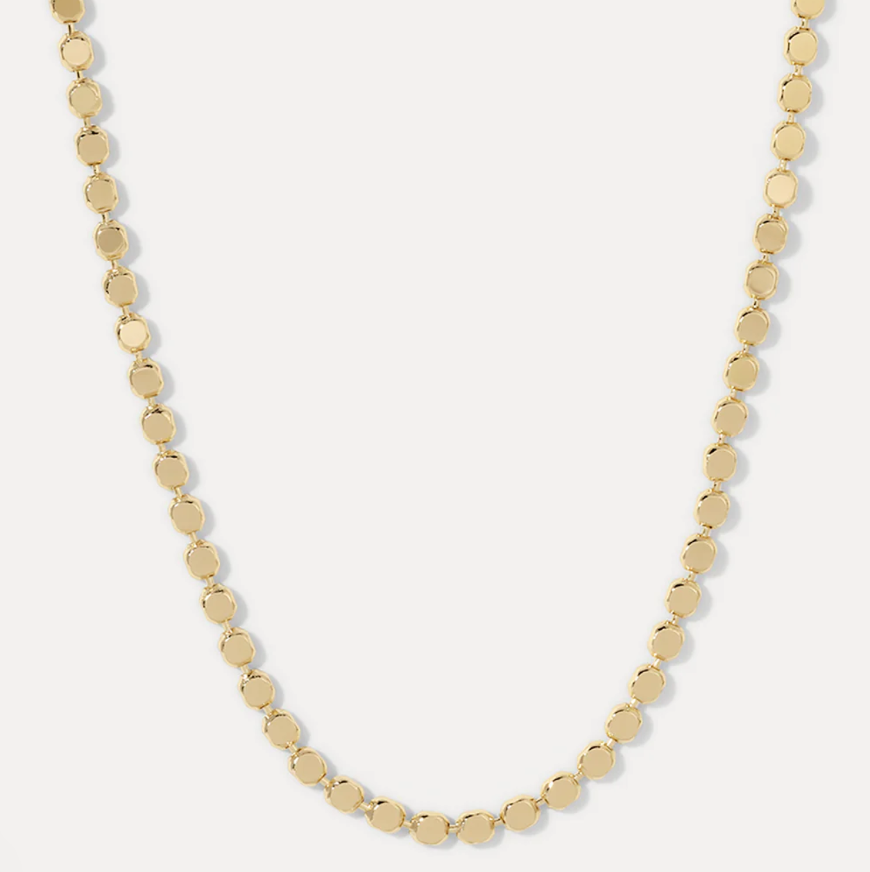 Gold discs necklace on a light gray background