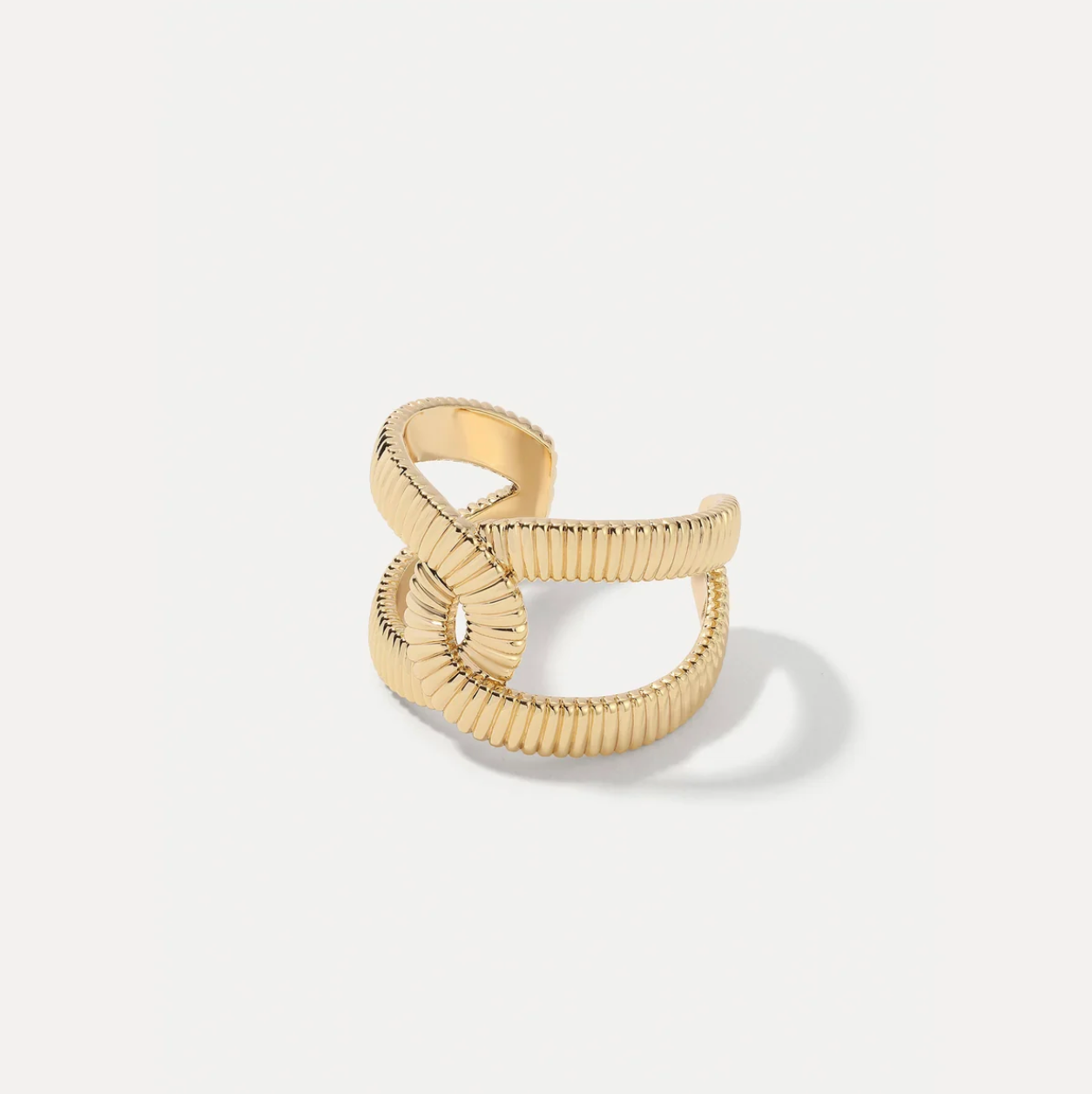 Gold ring with ribbed texture on a light gray background