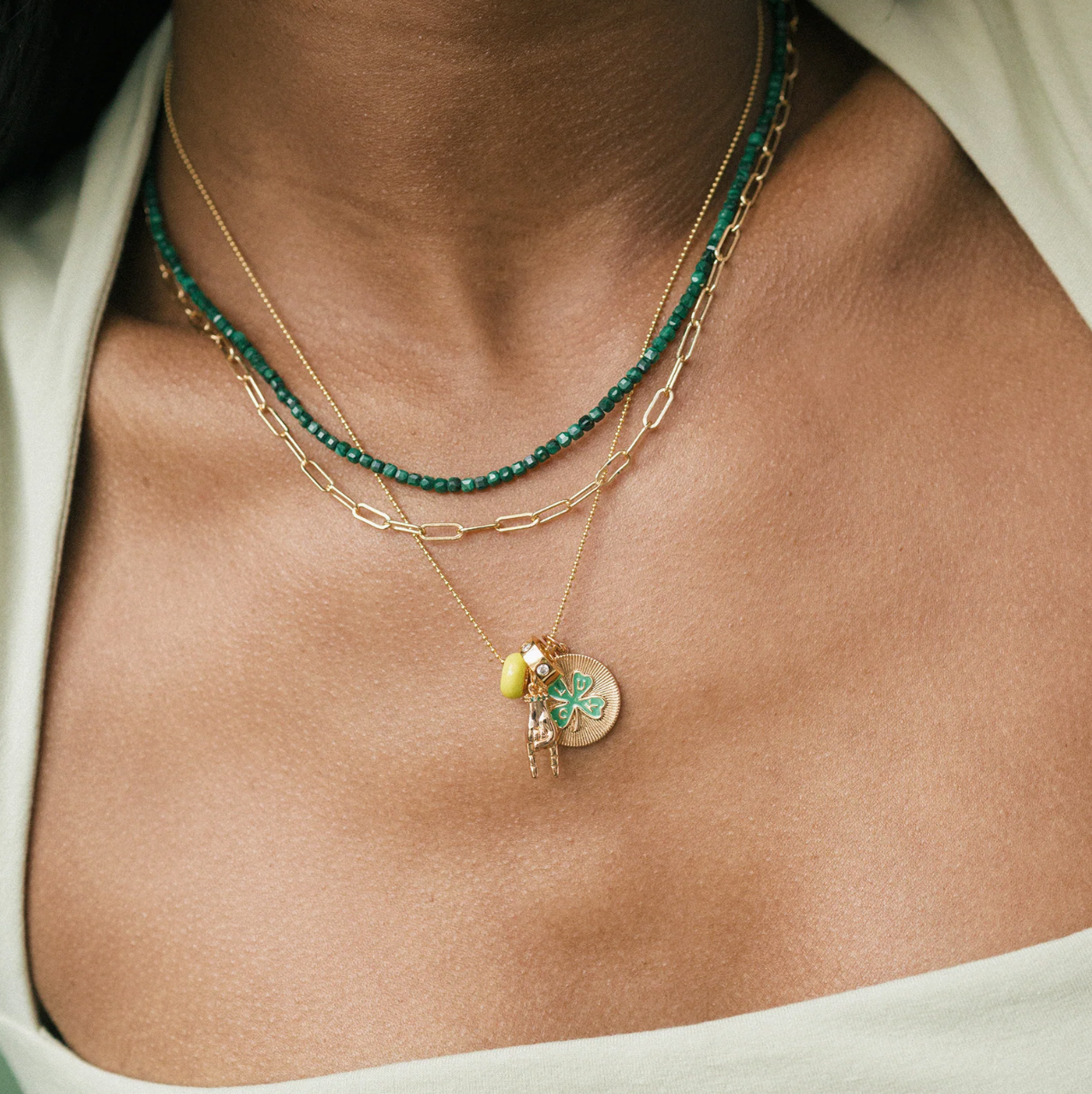 Necklace with green beads and gold chain  with Luck pendant worn by a person