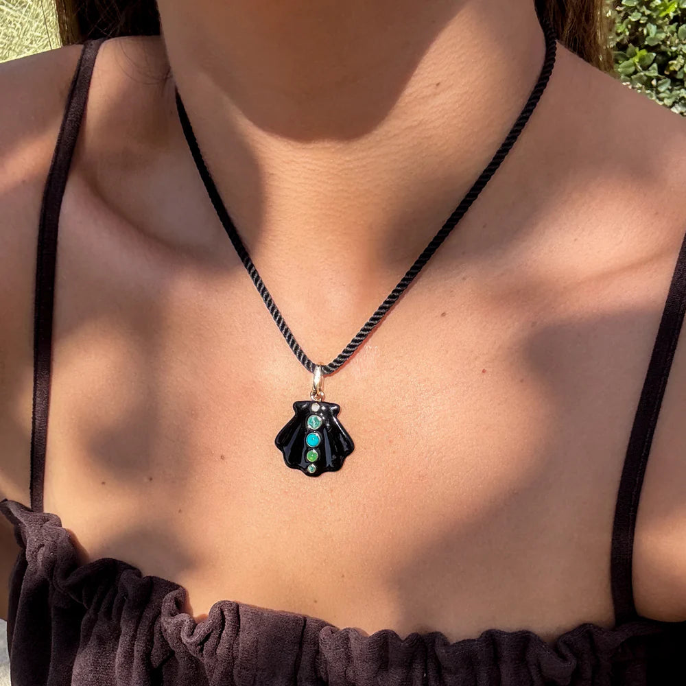 Person wearing a necklace with a black pendant featuring turquoise stones.