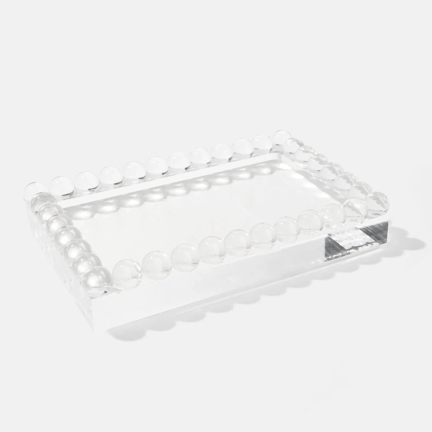 A clear acrylic rectangular tray with scalloped edges and raised circular bead detailing around the perimeter, shown on a light gray background.