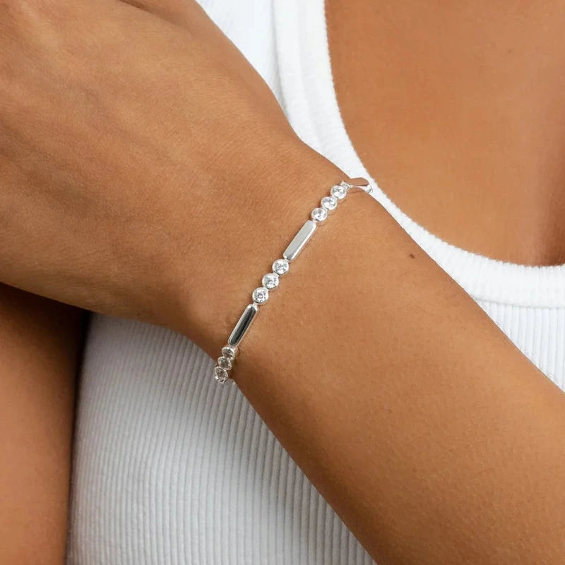 Silver bracelet on a wrist with a neutral background
