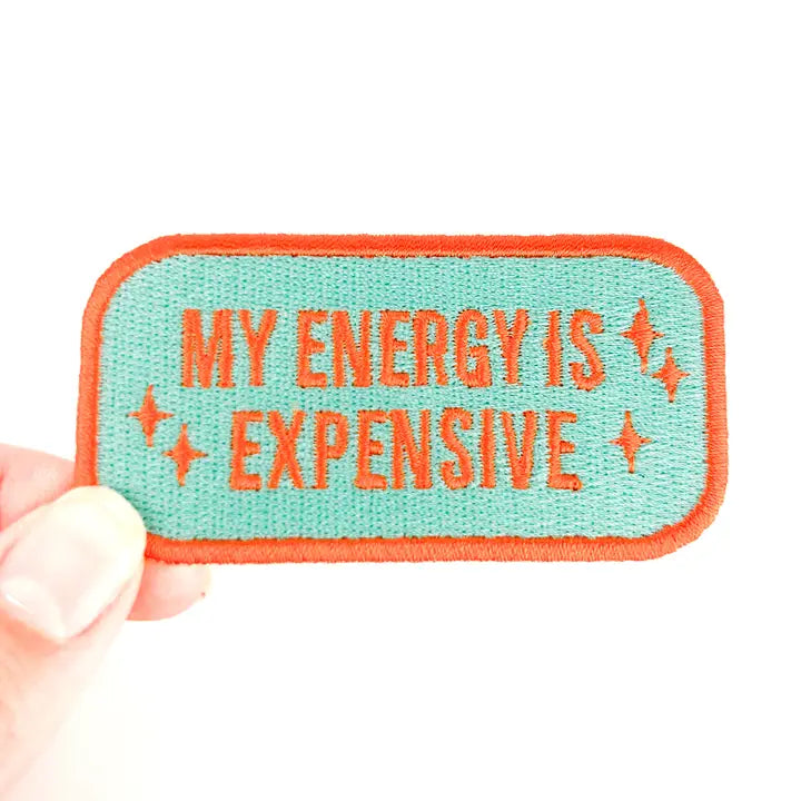 a turquoise and orange patch with text reading my energy is expensive on a white background