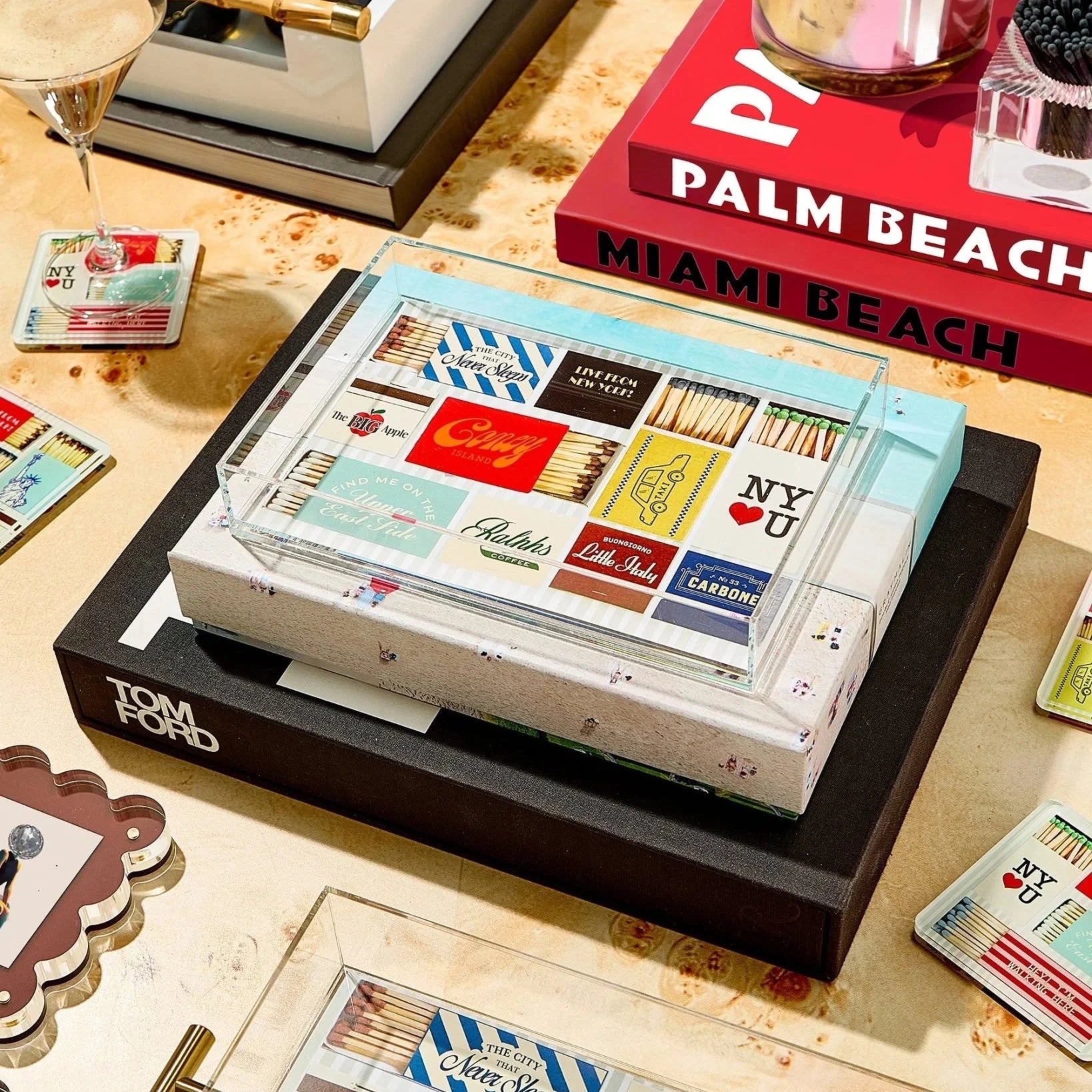a layflat of a tablescape with books, a martini, and a clear acrylic tray with matchbook covers in the design