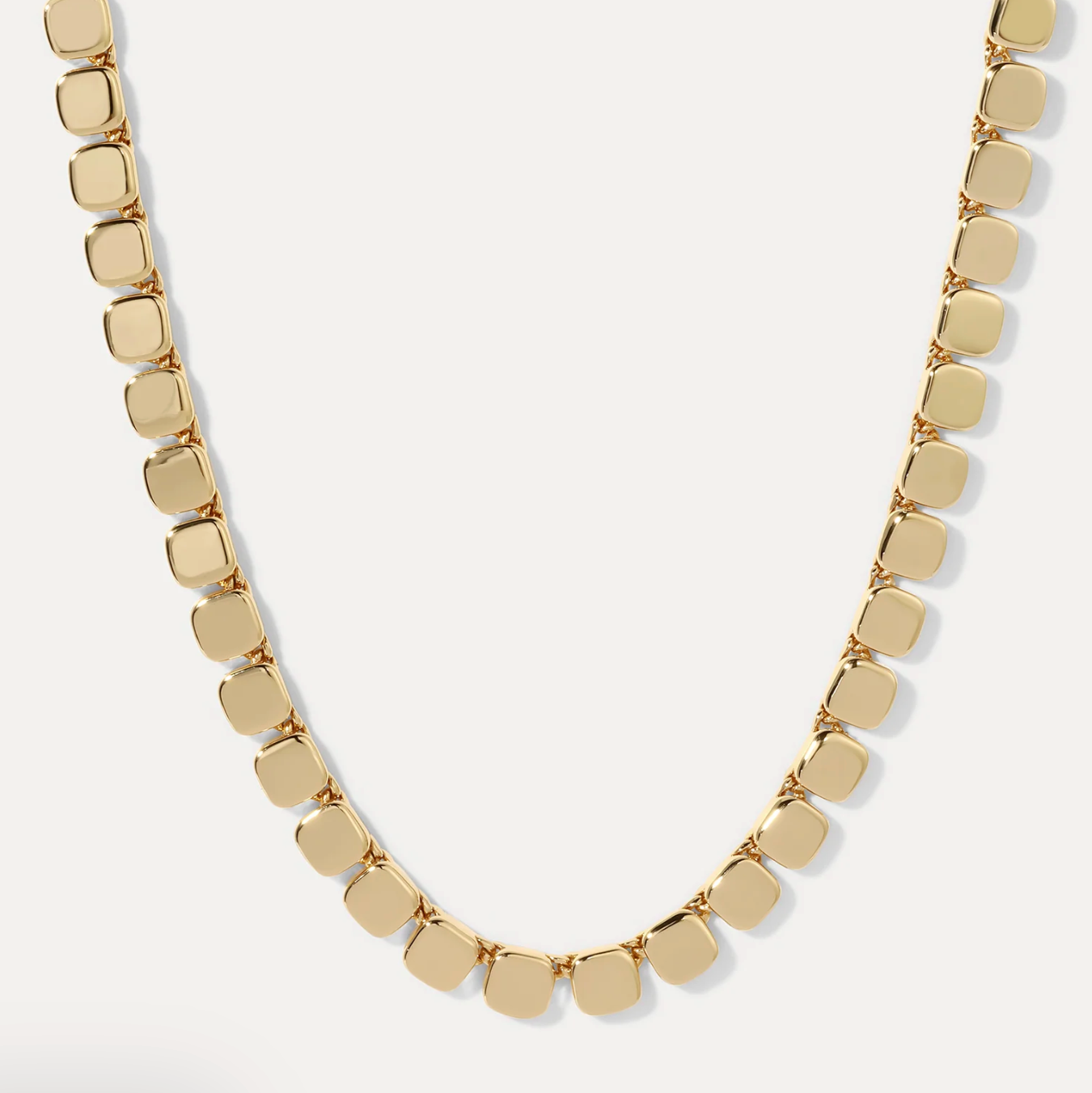 Gold necklace with square pendants on a white background