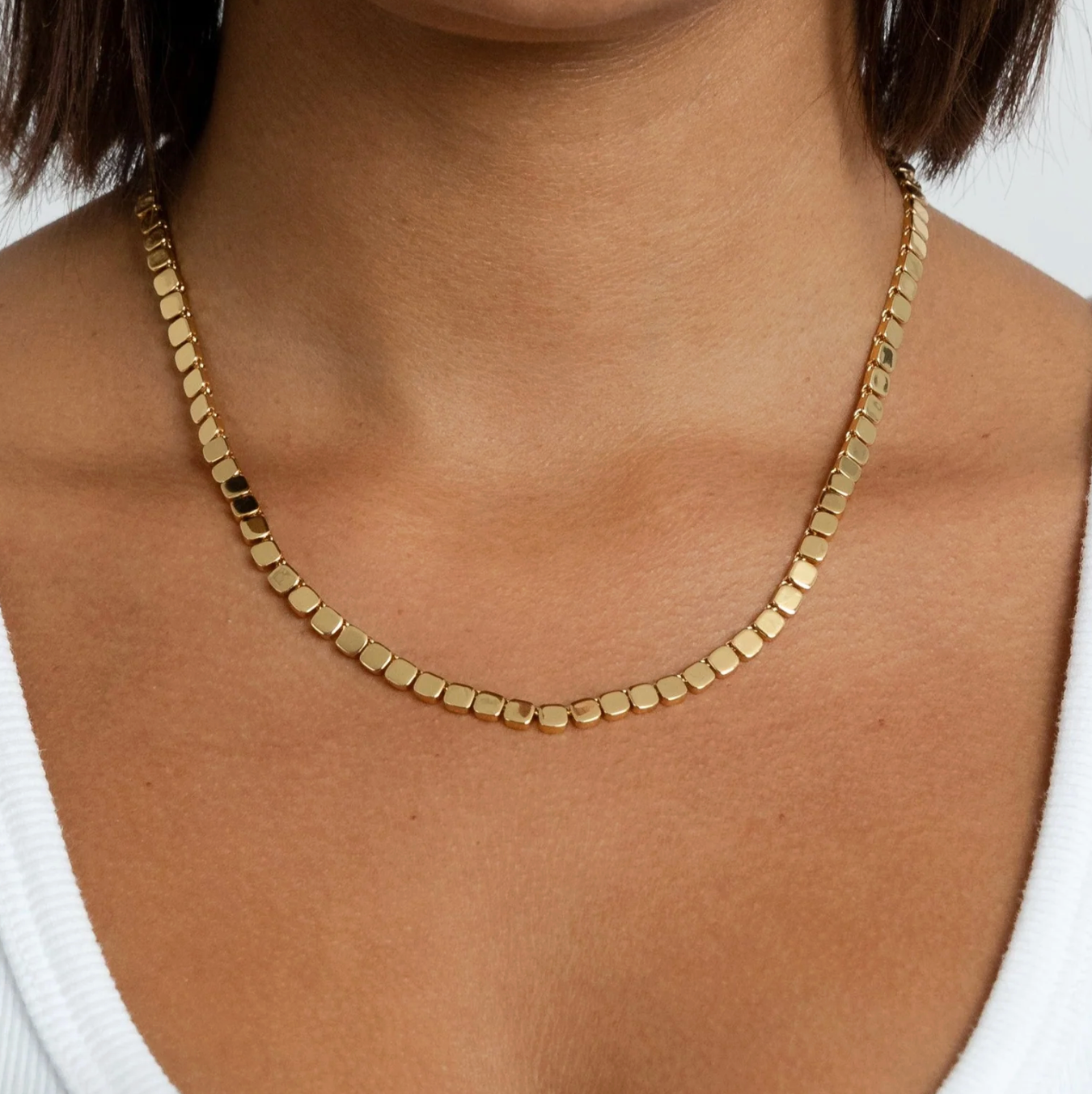 Gold necklace on a person with a white background