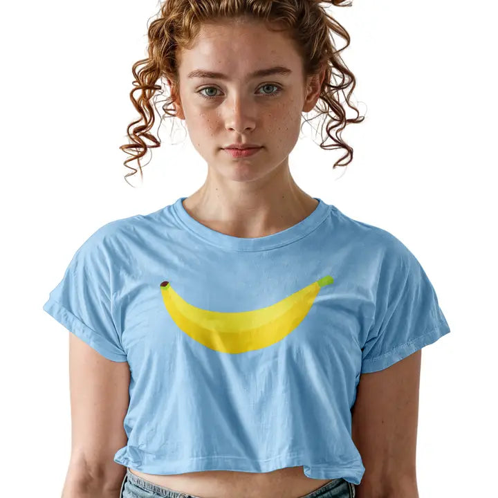 A young woman with curly light brown hair wearing a light blue cropped t-shirt with a yellow banana graphic on the front, set against a plain white background.