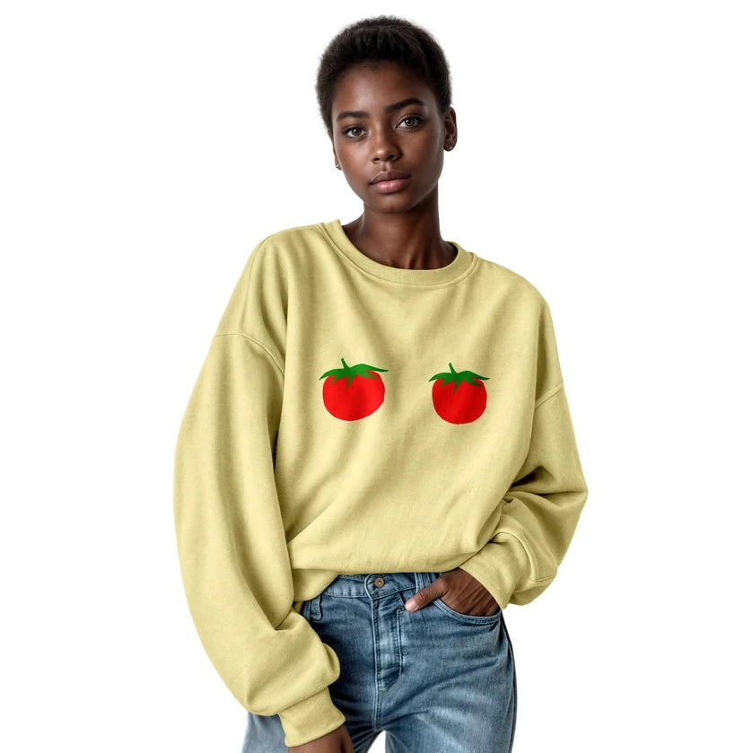 Person wearing a light yellow sweatshirt with tomato graphics on a white background