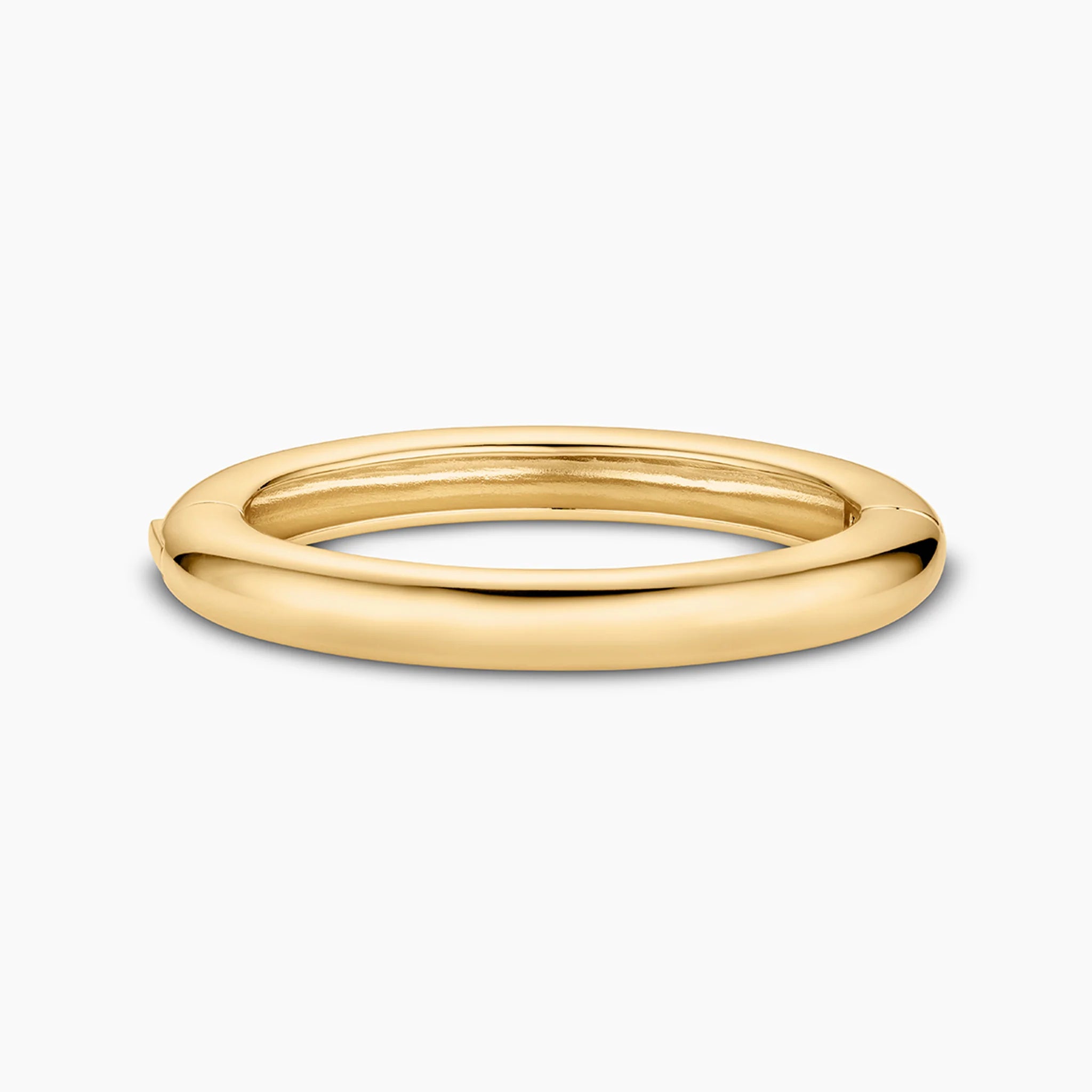 a thick gold bangle over a white background
