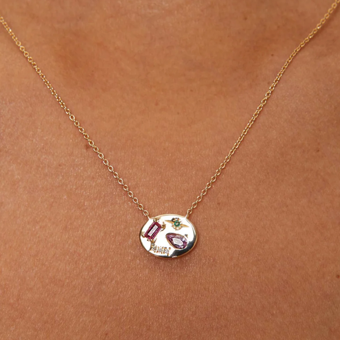 10k Gold necklace with a round pendant featuring pink and green gemstones and diamonds on a white background