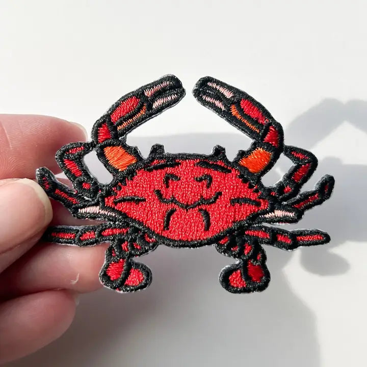 a red and black patch in the shape of a crab on a white background