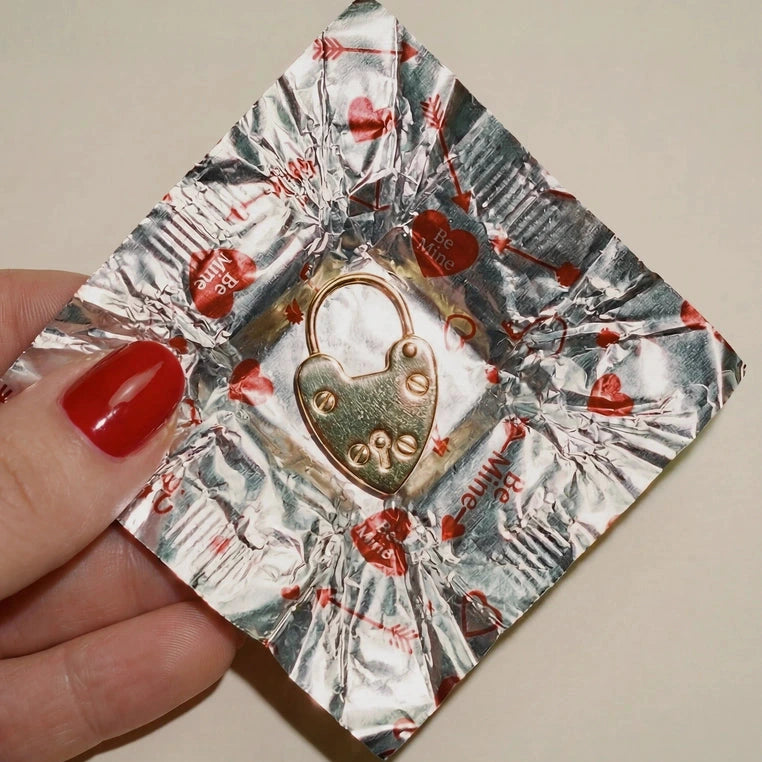 Decorative paper with a heart-shaped lock design held by a hand with red nail polish.