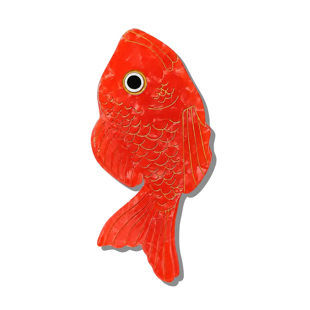 a red hair clip shaped like a fish with gold accents over a white background