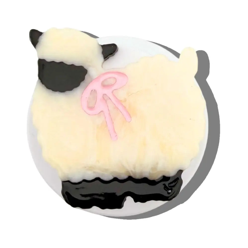 A stylized sheep-shaped product with fluffy cream-colored body, black face and lower section, and a pink bow detail on a white background.
