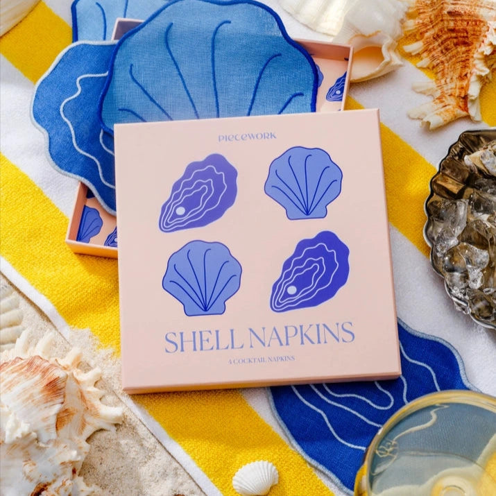 Pack of shell-themed napkins with blue shell designs on a yellow fabric background.