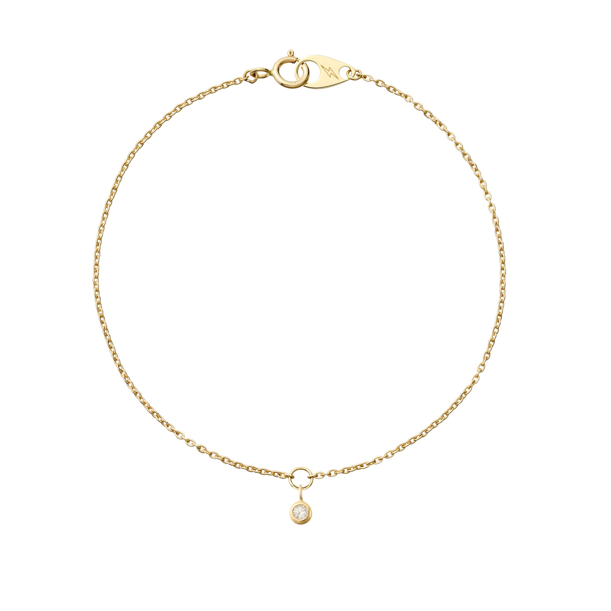 A delicate hanging 14k yellow gold birthstone on a 14k yellow gold mini cable bracelet on a white background