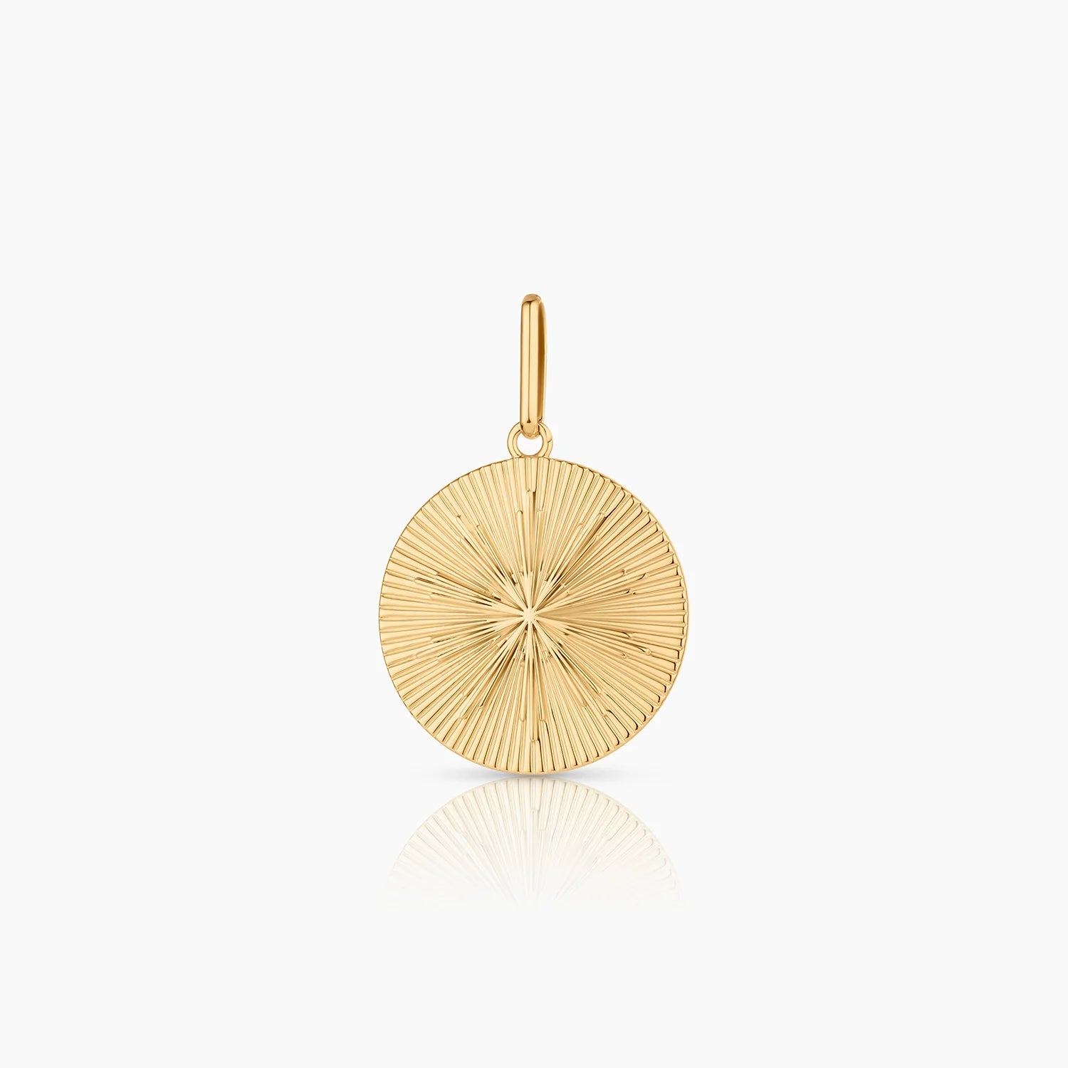 a circular gold charm with radiating grooves around a starburst design over a white background