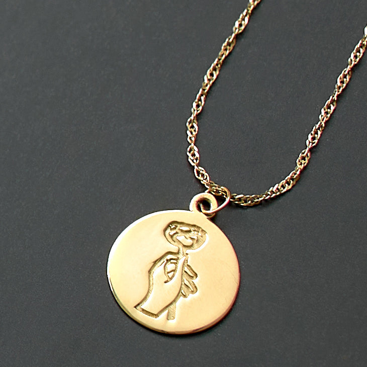 Gold necklace with a circular pendant on a dark gray background
