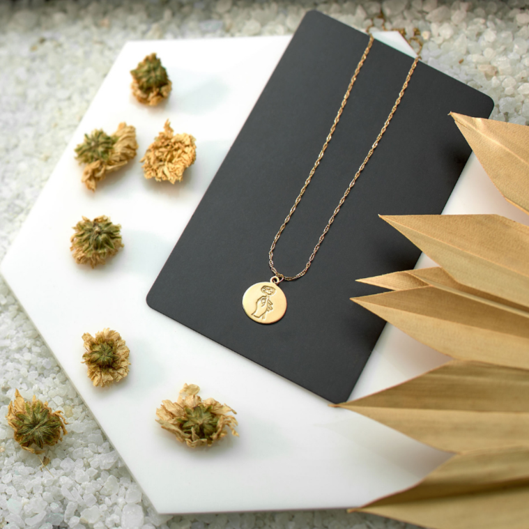 Gold necklace and earrings on a black card with decorative elements