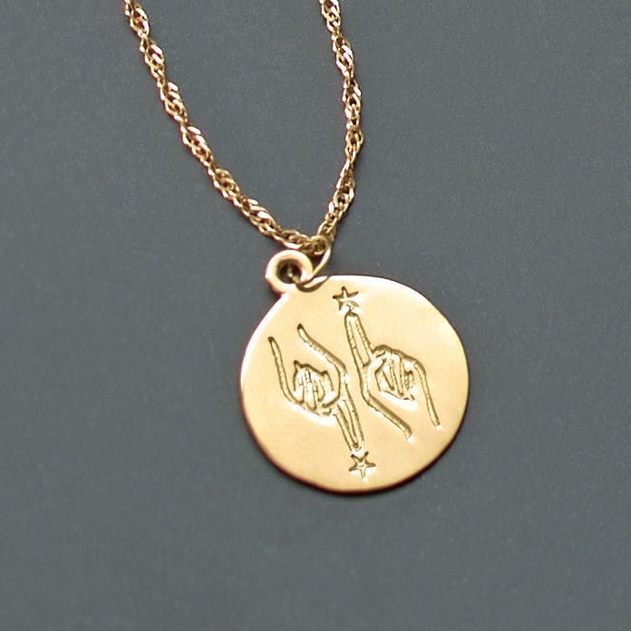 Gold necklace with a round pendant on a gray background