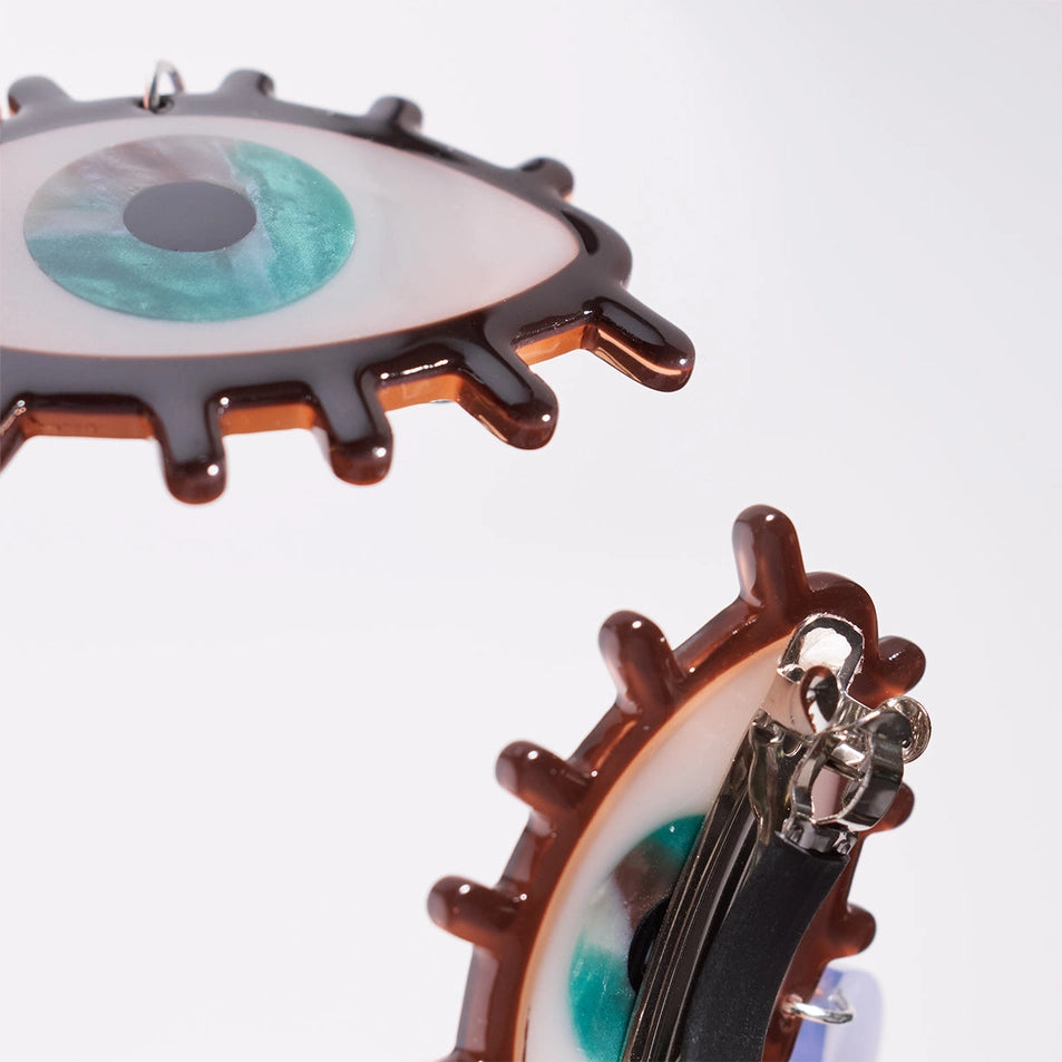 close up of the front and back of two french barrette clips in the shape of an eye over a white background