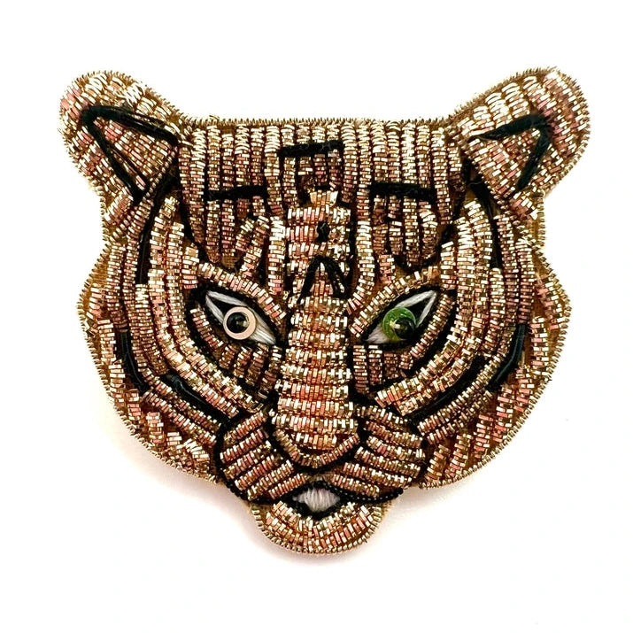 a gold and black tiger brooch on a white background