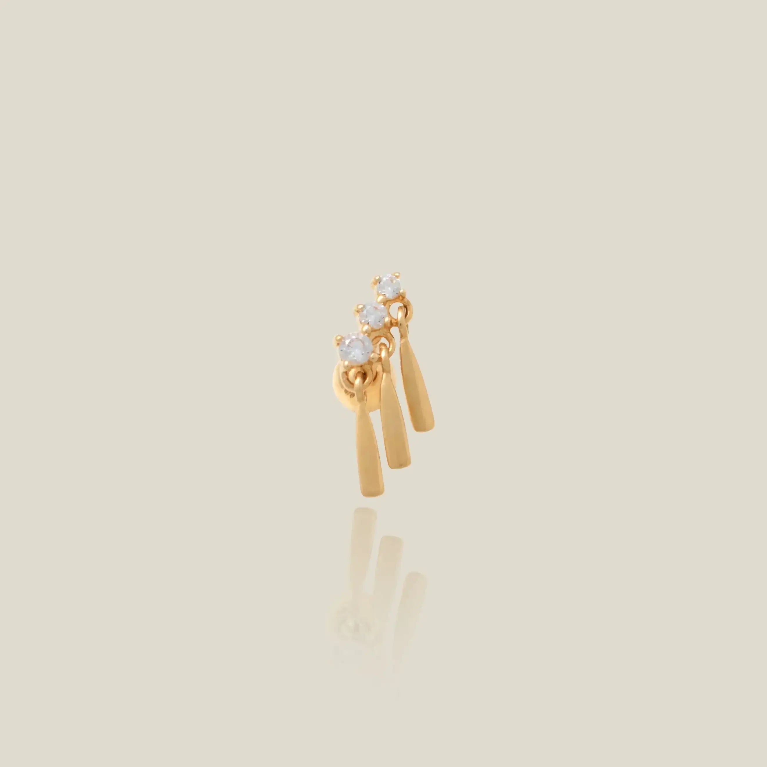 Gold earring with three bars and three circular elements on a beige background