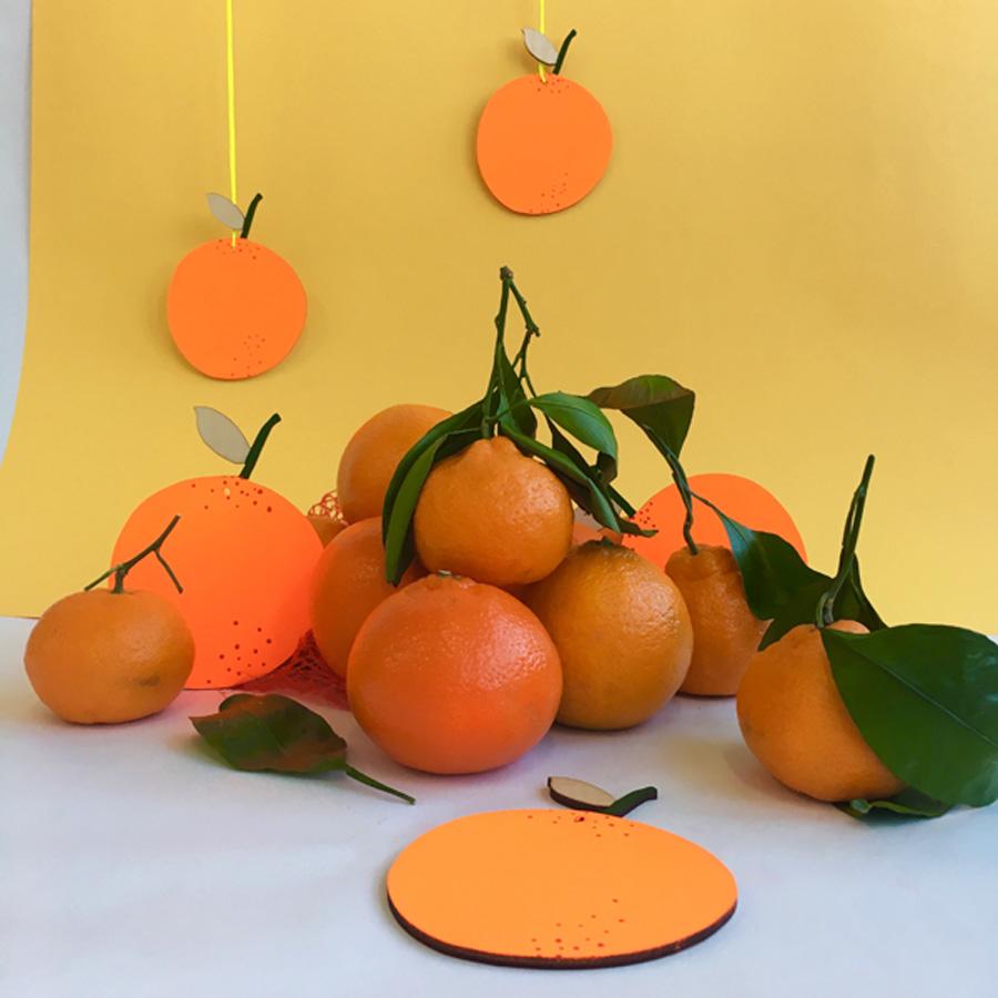 Oranges with green leaves on a white surface against a yellow background