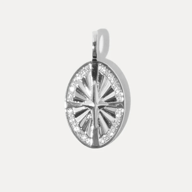 an oval shaped silver charm with a star motif and stone accents on a white background