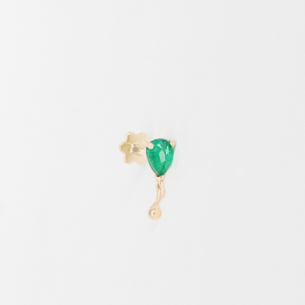 Celine Daoust 14k light yellow gold flat back piercing with one pear shaped emerald and gold drop. The stone comes in a gradient of vivid green on white background