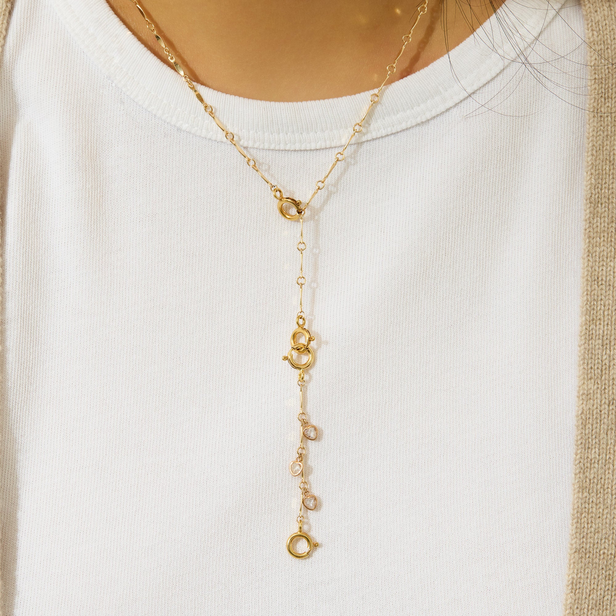 Gold necklace with a lariat design on a white background