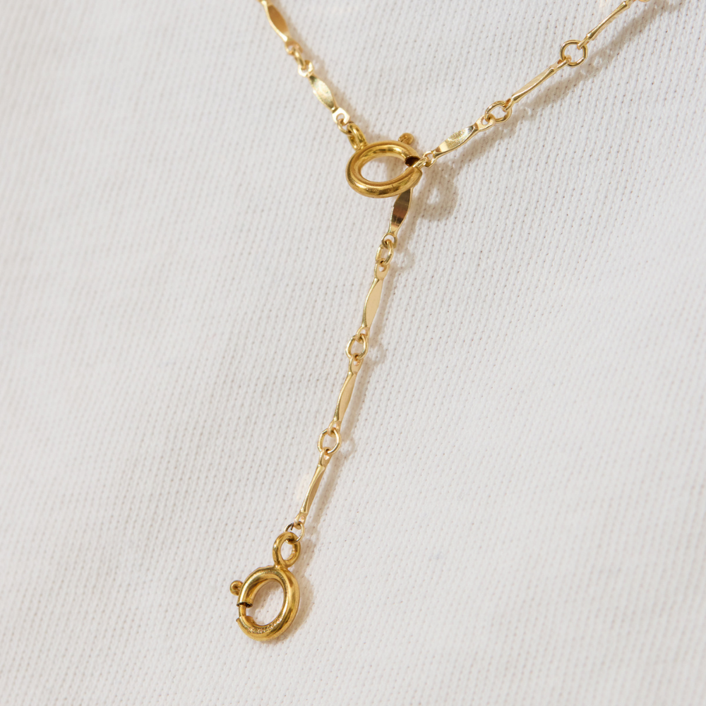 Gold necklace with a clasp on a light gray background