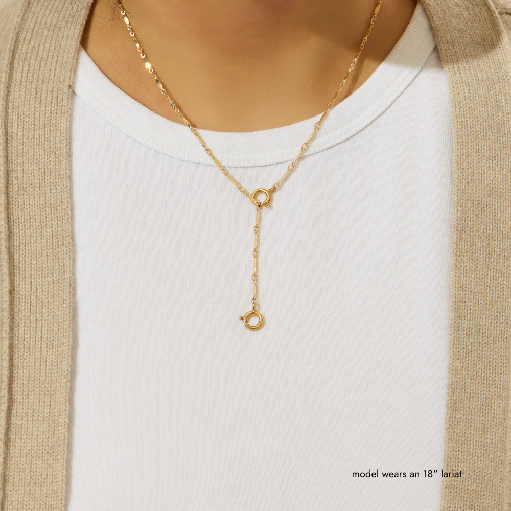 Gold necklace worn by a model on a plain background