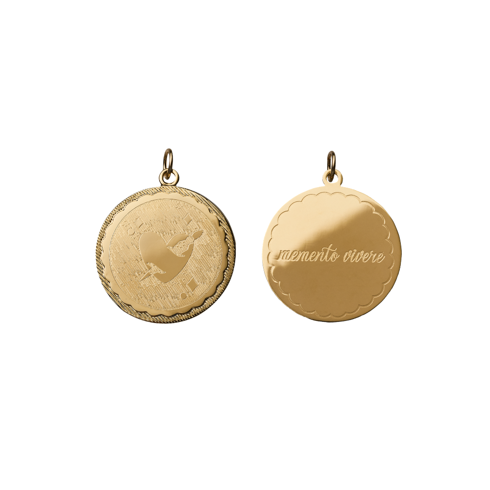 double sided engraved coin with a pierced heart on one side and memento vivere on the other side on white background
