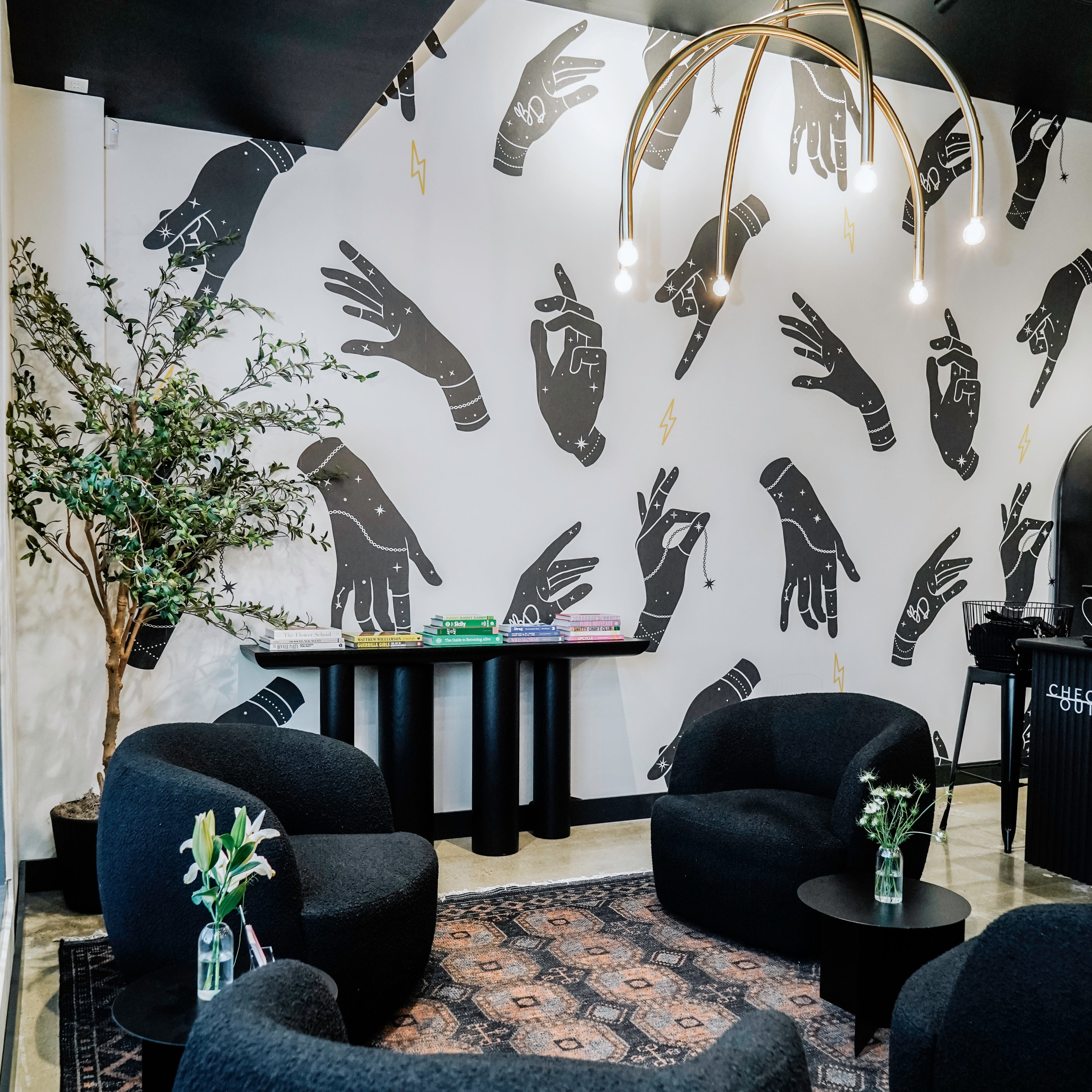 Modern jewelry store interior with black armchairs, decorative wall art, and a chandelier.