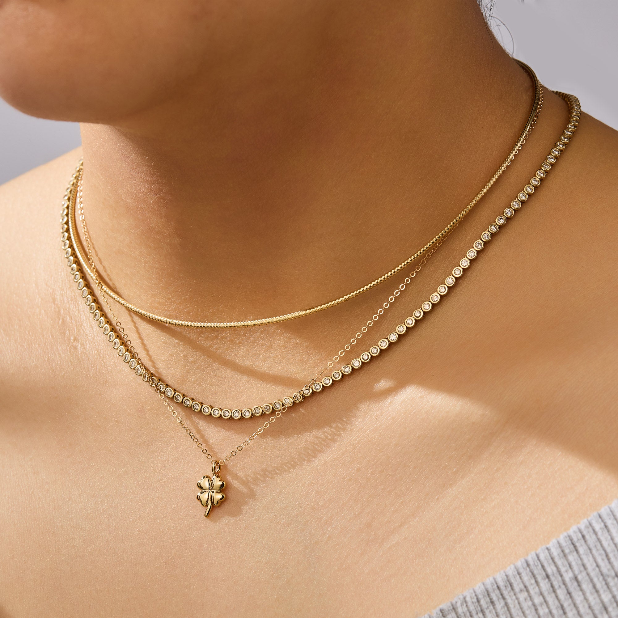 Close-up of a person wearing two gold necklaces with a subtle background