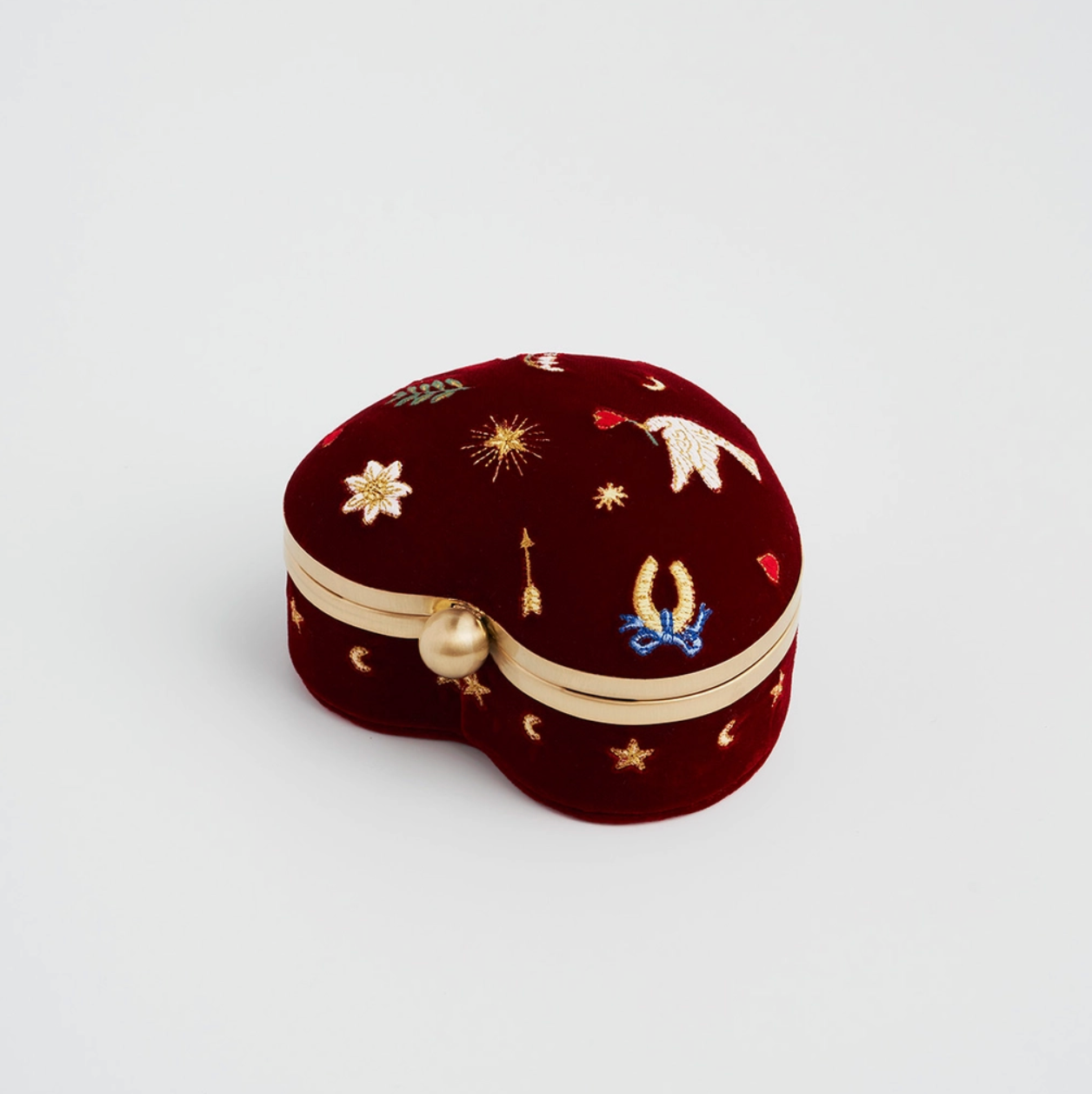 Heart-shaped jewelry box with embroidered designs on a light gray background