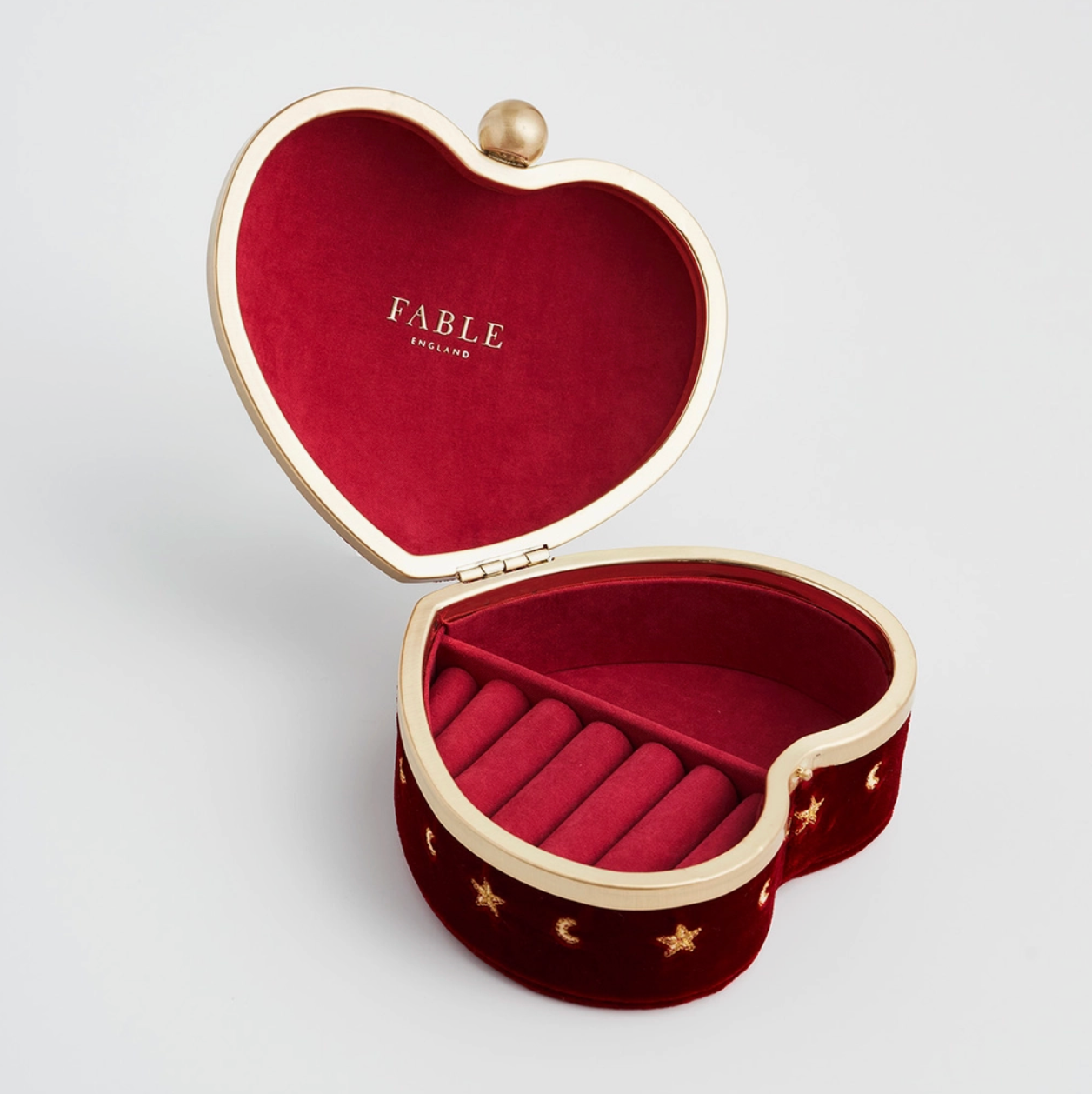 Heart-shaped jewelry box with red interior and gold accents, featuring the brand 'Fable'.