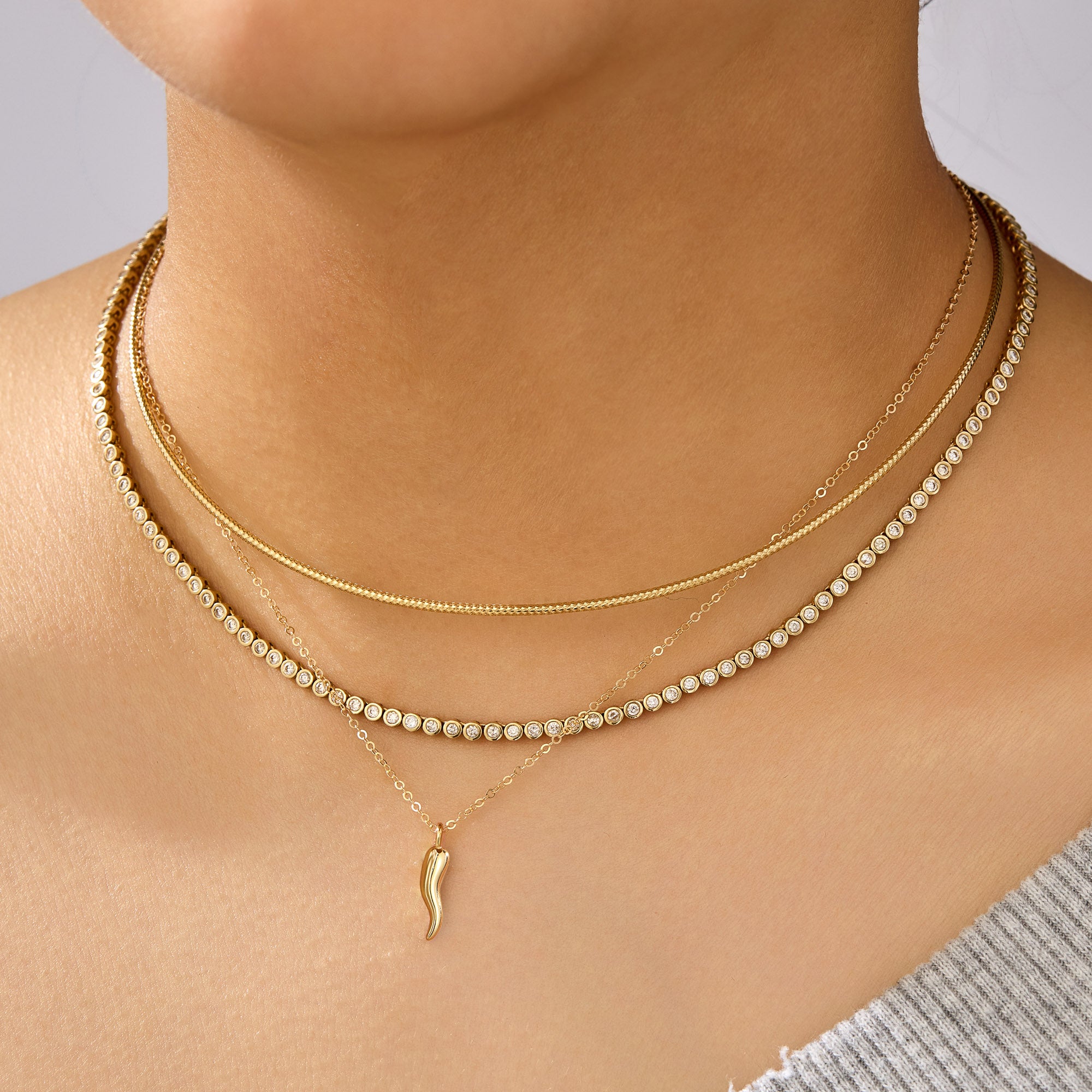 Gold necklaces on a person's neck with a plain background