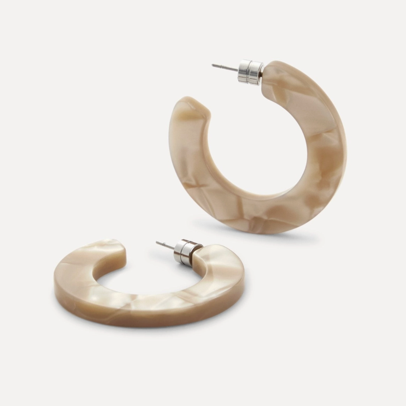 Pair of beige hoop earrings on a light gray background