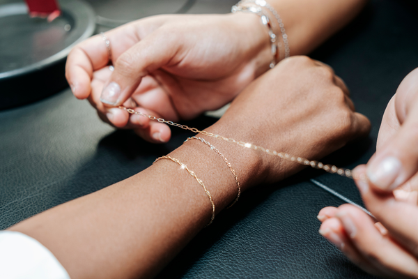 Brave Daughters jewelry artist measuring and fitting a custom 14k gold chain for a permanent bracelet in the studio.