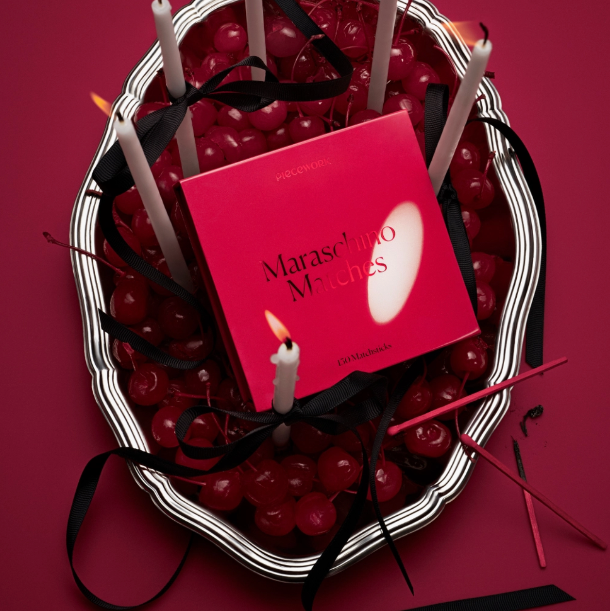 Maraschino cherry bowl with a red matchbook titled 'Maraschino Matches' on a red background