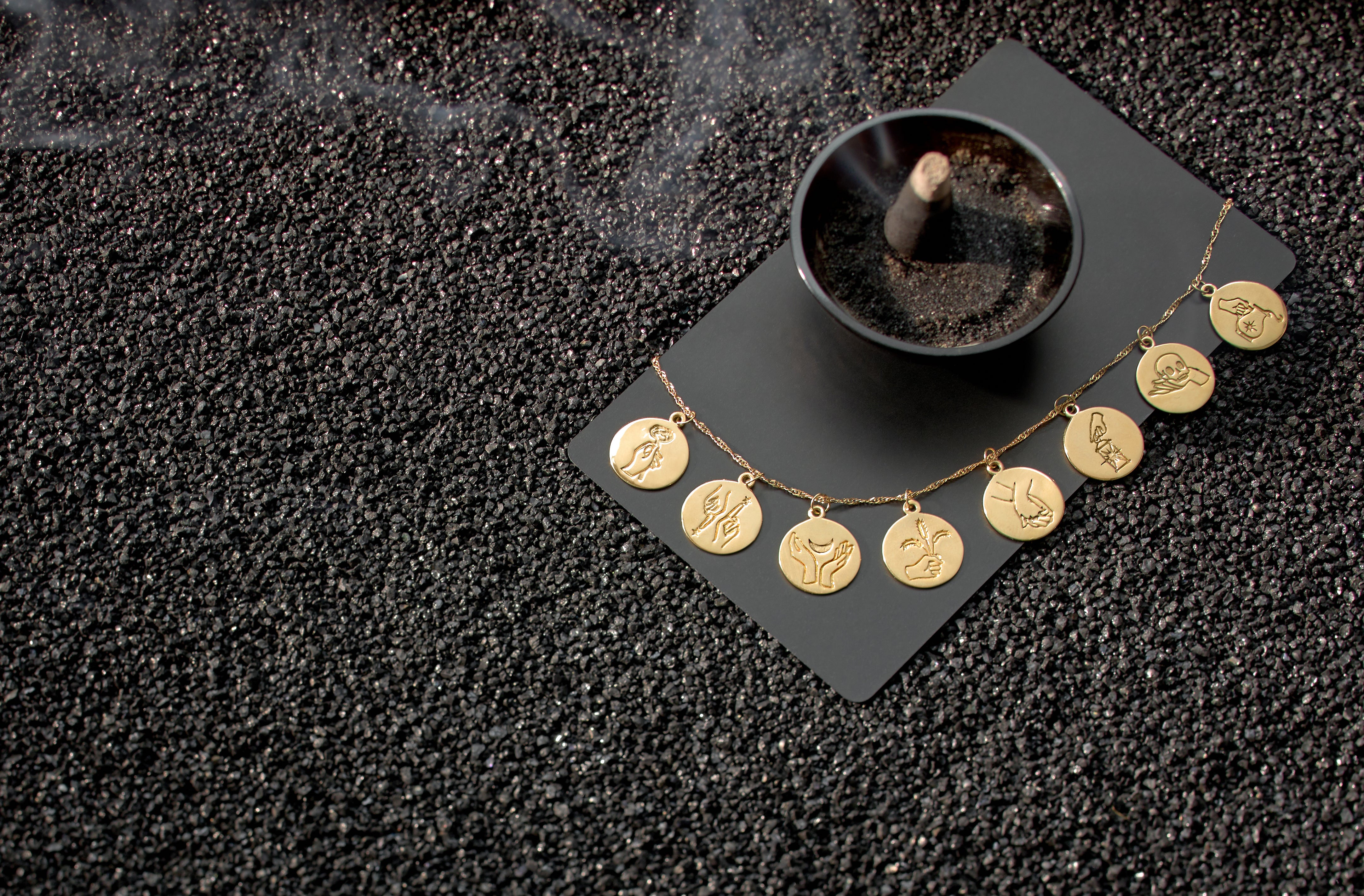 Gold necklace with circular pendants on a dark textured surface